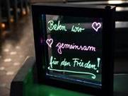 Eine beleuchtete Tafel mit der Aufschrift: wir beten gemeinsam für den Frieden