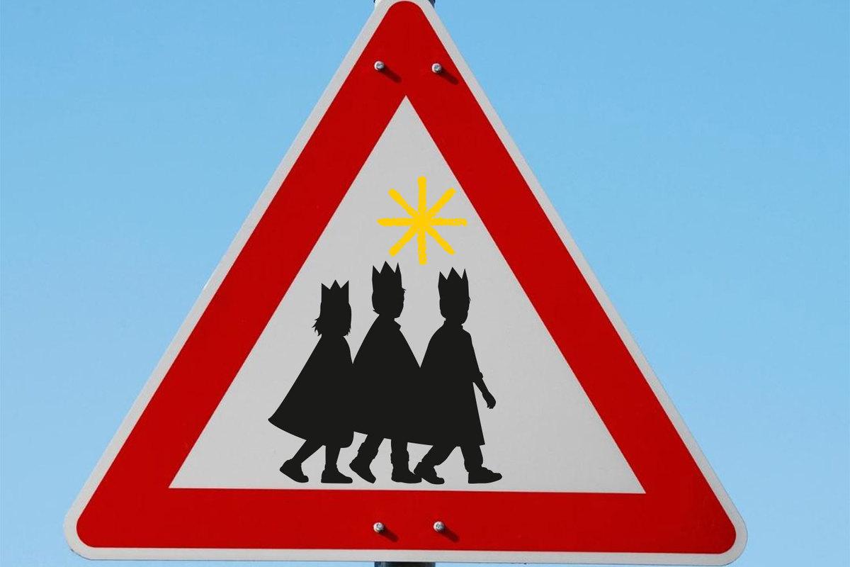 EIne Gruppe von Kindern mit Kronen und Umhängen in einem dreieckigen Straßenschild